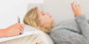 Therapist taking notes on her patient on the sofa at therapy ses